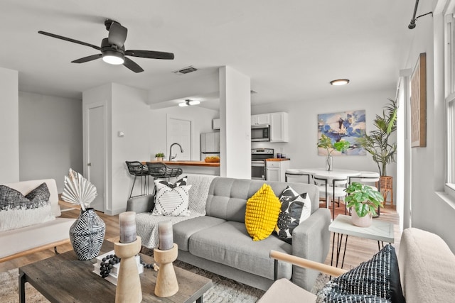 living room featuring ceiling fan and light hardwood / wood-style flooring