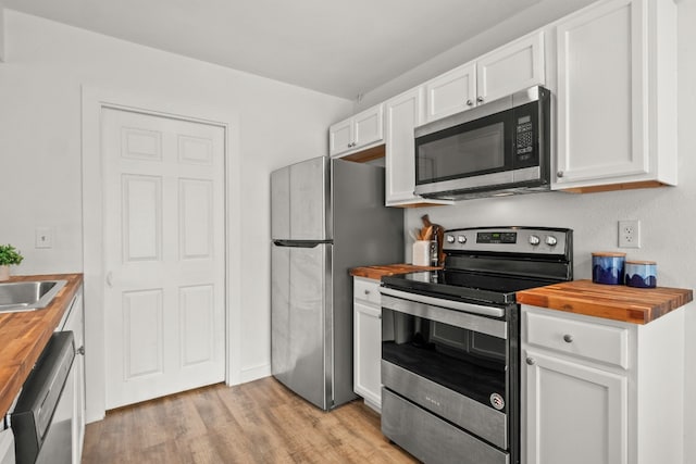 kitchen with white cabinets, wooden counters, light hardwood / wood-style flooring, and appliances with stainless steel finishes