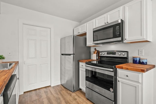 5616 Emerald Forest Dr Unit 101, Austin, TX 78745 - kitchen with butcher block counters, stainless steel appliances, light wood-style flooring, and white cabinets