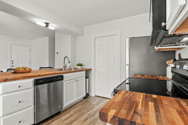 kitchen with stainless steel appliances, wooden counters, white cabinetry, sink, and light hardwood / wood-style floors