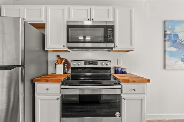 kitchen featuring butcher block counters, white cabinets, and stainless steel appliances