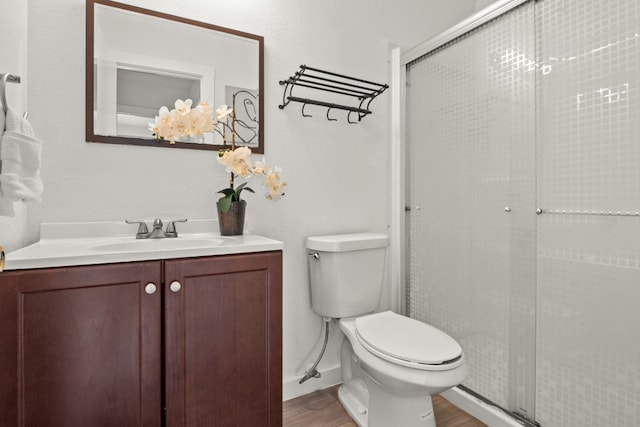 bathroom with toilet, vanity, hardwood / wood-style floors, and a shower with shower door