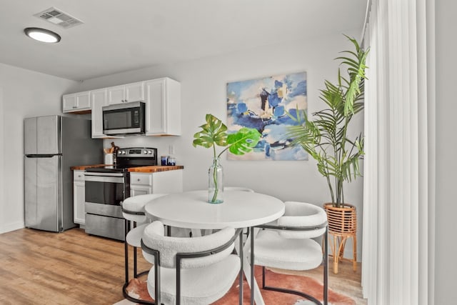 kitchen with white cabinetry, light wood-type flooring, appliances with stainless steel finishes, and wood counters