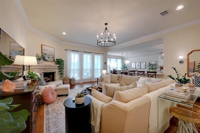 living room featuring ornamental molding, a chandelier, a fireplace, and hardwood / wood-style flooring