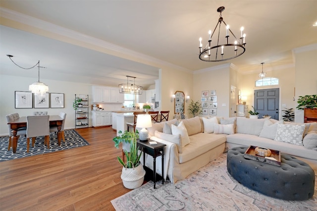 living room featuring light hardwood / wood-style flooring, a chandelier, and crown molding