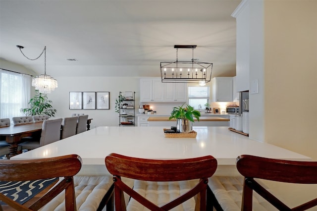 kitchen with light hardwood / wood-style floors, a notable chandelier, decorative light fixtures, and white cabinets