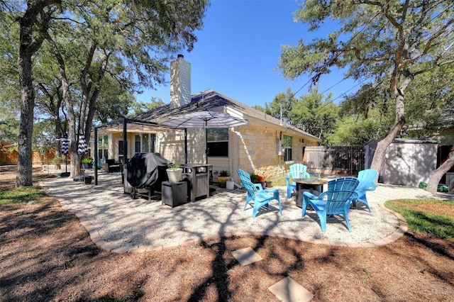 rear view of property featuring a patio and a fire pit