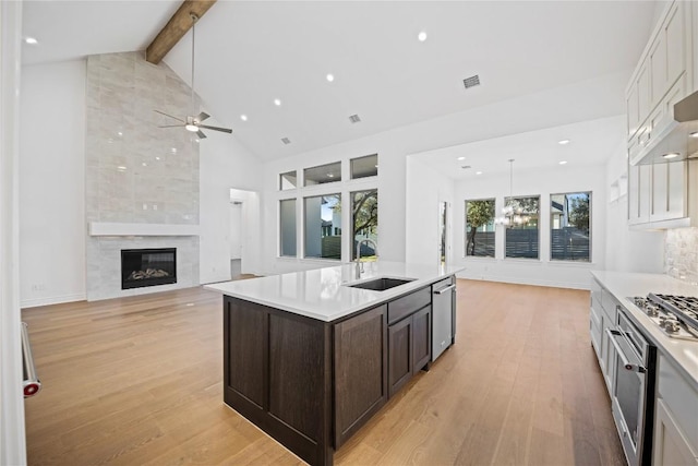 kitchen with dark brown cabinetry, sink, decorative light fixtures, and a kitchen island with sink