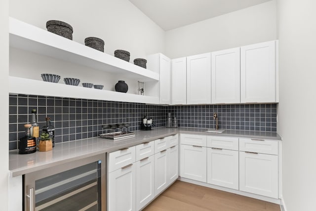 kitchen with light hardwood / wood-style floors, white cabinetry, backsplash, and beverage cooler