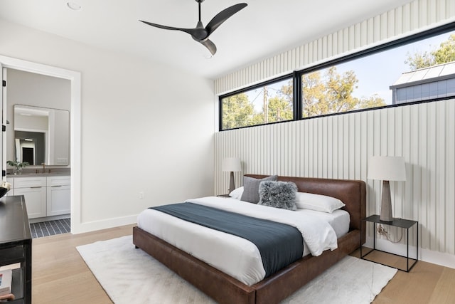 bedroom with ceiling fan, ensuite bathroom, and light hardwood / wood-style flooring