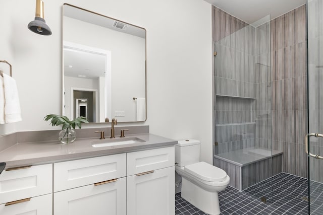 bathroom featuring a tile shower, tile patterned flooring, vanity, and toilet