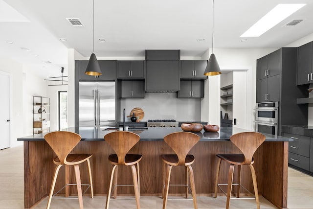 kitchen featuring decorative light fixtures, stainless steel appliances, a breakfast bar area, and exhaust hood