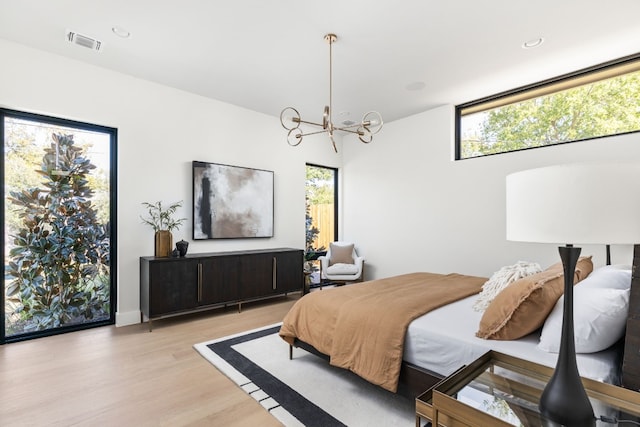 bedroom featuring multiple windows, a chandelier, and light hardwood / wood-style floors