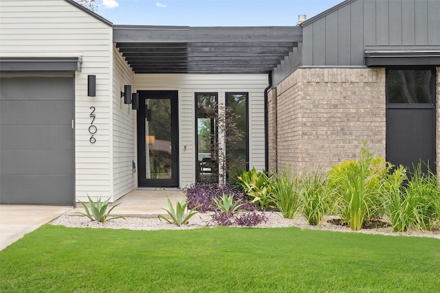 view of exterior entry featuring a lawn and a garage