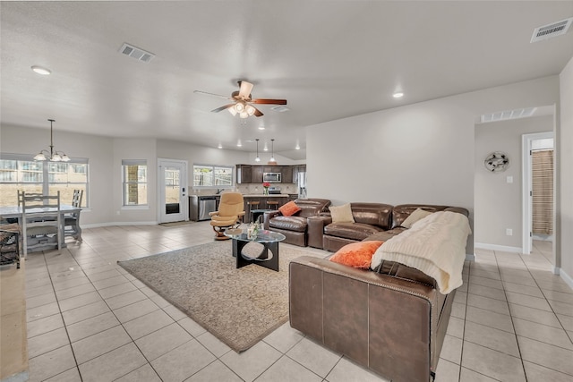 tiled living room with ceiling fan with notable chandelier