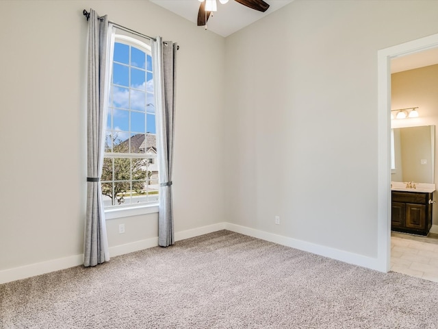 carpeted spare room with a wealth of natural light, ceiling fan, and sink