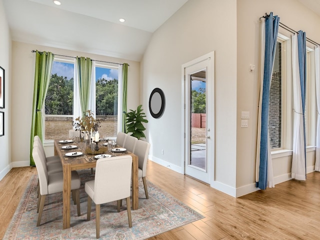 dining room featuring light wood-type flooring and vaulted ceiling