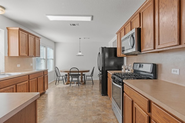 kitchen with appliances with stainless steel finishes, decorative light fixtures, and sink