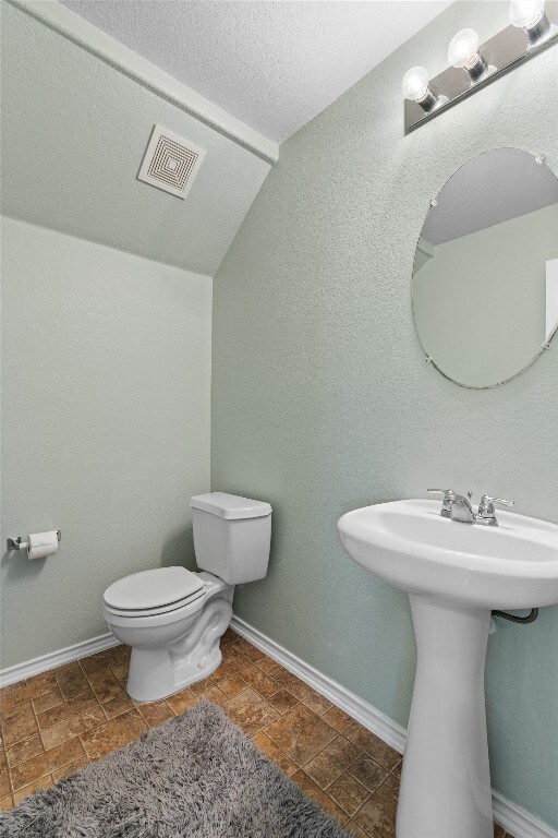 bathroom with lofted ceiling, sink, and toilet