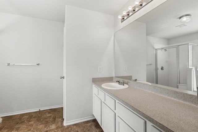 bathroom featuring a shower with door and vanity