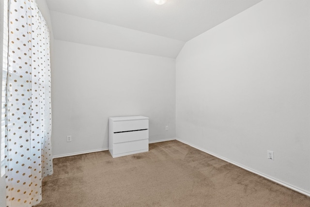 spare room with lofted ceiling and light colored carpet