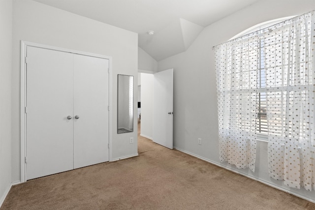 unfurnished bedroom featuring a closet, vaulted ceiling, and light colored carpet