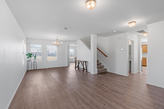 unfurnished living room with dark wood-type flooring and an inviting chandelier