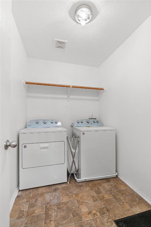 clothes washing area with a textured ceiling and separate washer and dryer