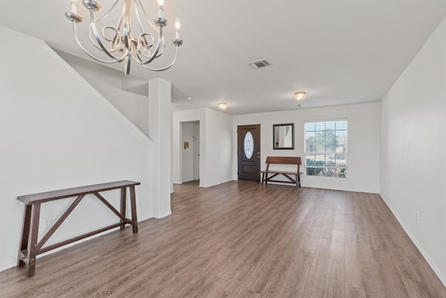 unfurnished living room with a notable chandelier and wood-type flooring