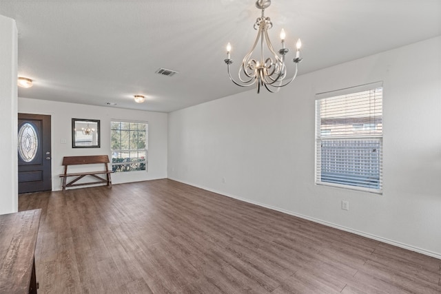 unfurnished living room featuring a notable chandelier and hardwood / wood-style flooring