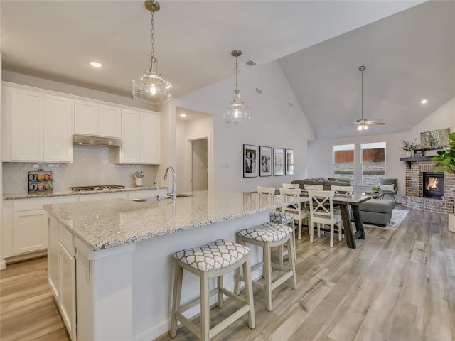 kitchen with white cabinetry, sink, ceiling fan, and a kitchen island with sink