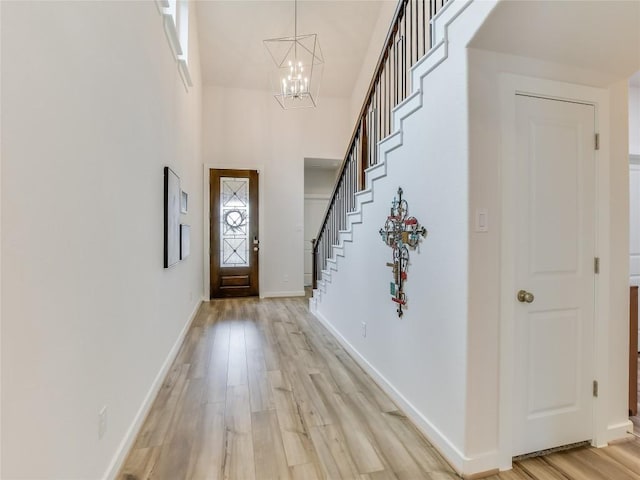 foyer featuring a chandelier, a towering ceiling, and light hardwood / wood-style flooring