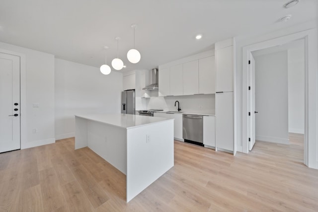 kitchen with a kitchen island, light hardwood / wood-style flooring, white cabinets, decorative light fixtures, and appliances with stainless steel finishes