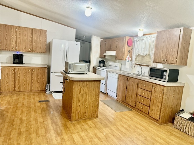 kitchen with white appliances, sink, light wood-type flooring, a textured ceiling, and a center island