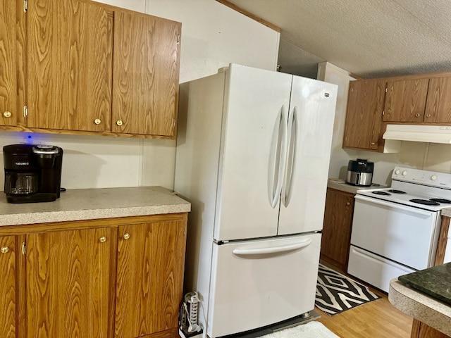 kitchen with light hardwood / wood-style flooring, a textured ceiling, and white appliances