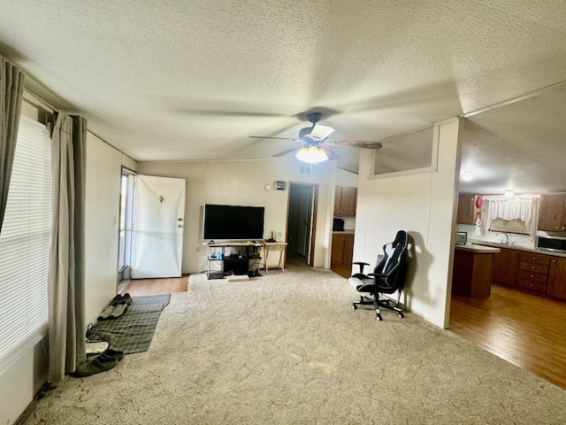 interior space featuring light hardwood / wood-style flooring, a textured ceiling, lofted ceiling, and ceiling fan