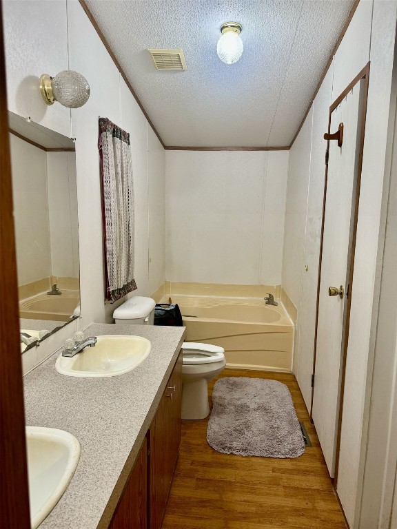 bathroom featuring a textured ceiling, toilet, a tub, and hardwood / wood-style flooring