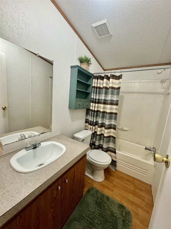 full bathroom featuring a textured ceiling, shower / bath combo, toilet, vanity, and hardwood / wood-style flooring