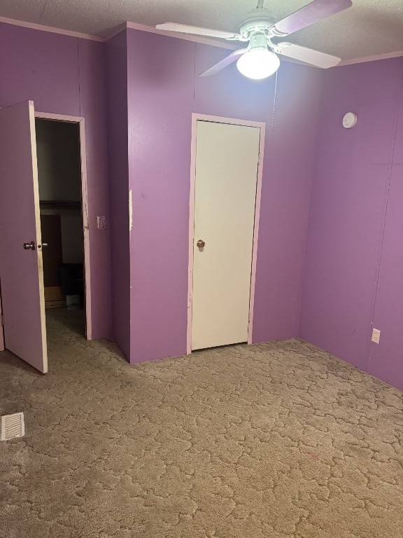 unfurnished bedroom featuring crown molding, a textured ceiling, carpet floors, and ceiling fan