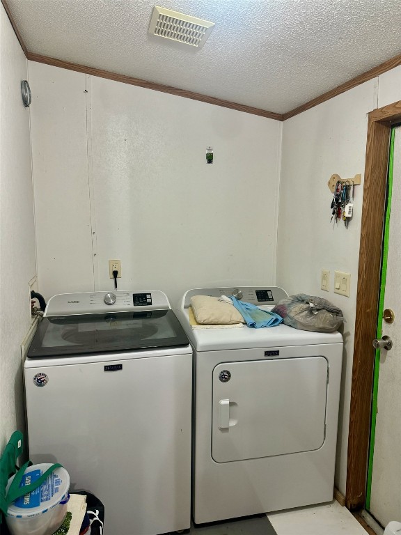 laundry room featuring crown molding, a textured ceiling, and separate washer and dryer