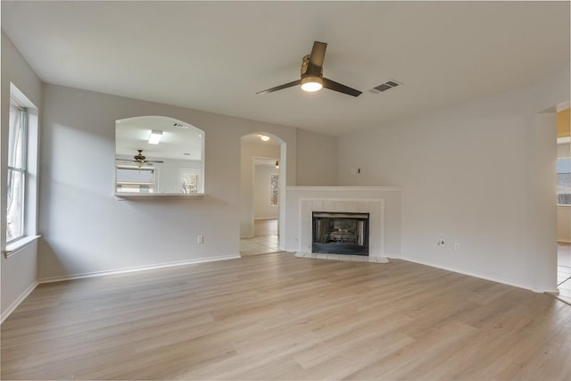 unfurnished living room featuring ceiling fan, a fireplace, and light hardwood / wood-style flooring