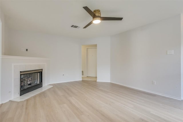 unfurnished living room featuring ceiling fan, a fireplace, and light hardwood / wood-style flooring