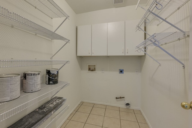 washroom featuring gas dryer hookup, cabinets, light tile patterned floors, electric dryer hookup, and washer hookup