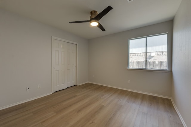 unfurnished bedroom featuring ceiling fan, a closet, and light hardwood / wood-style flooring