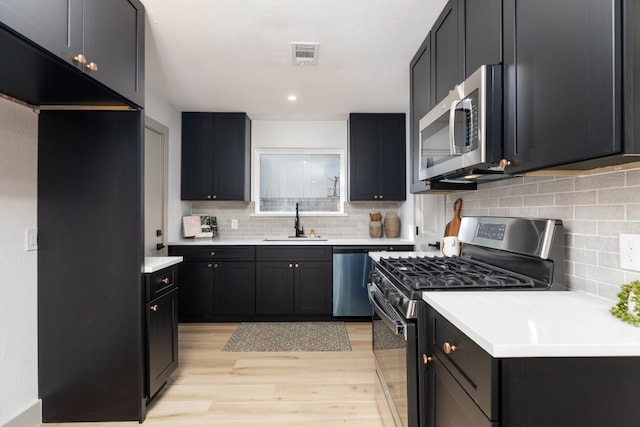 kitchen with decorative backsplash, stainless steel appliances, light hardwood / wood-style floors, and sink