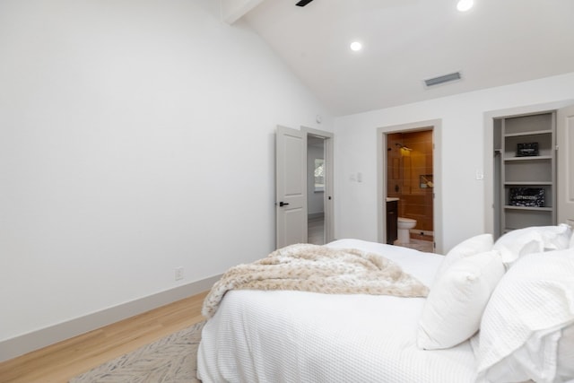 bedroom with ensuite bath, a closet, light hardwood / wood-style flooring, and lofted ceiling with beams