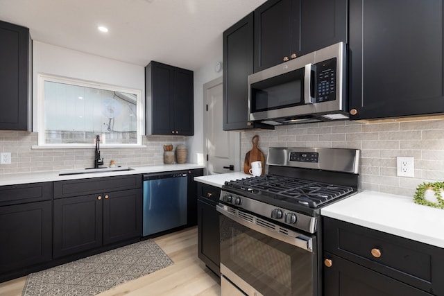 kitchen featuring appliances with stainless steel finishes, backsplash, light hardwood / wood-style floors, and sink