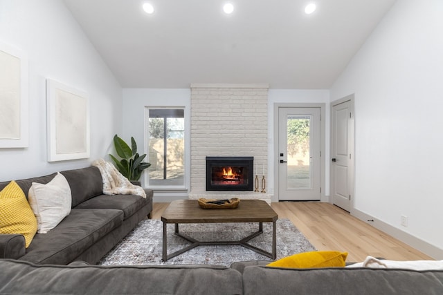 living room with light hardwood / wood-style floors, a fireplace, and vaulted ceiling