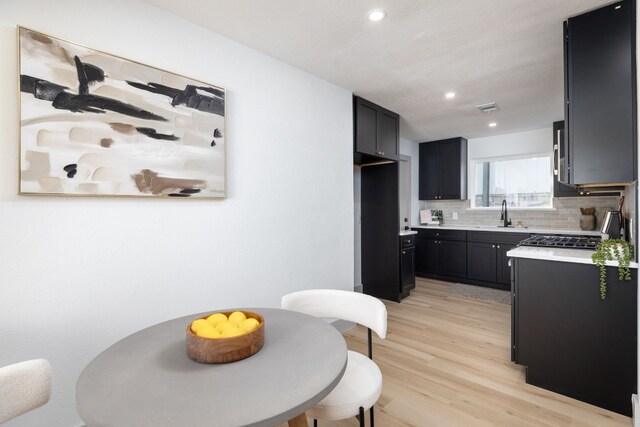 kitchen with decorative backsplash, light hardwood / wood-style floors, range, and sink