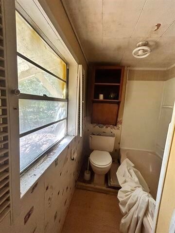 bathroom featuring toilet and a tub to relax in